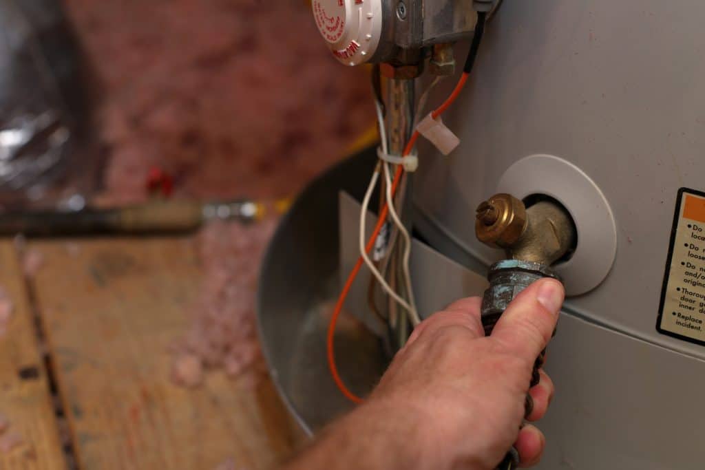 Hand attaches hose to water heater