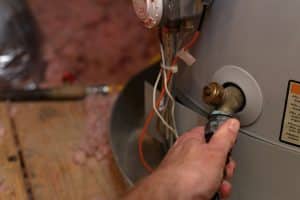 Hand attaches hose to water heater